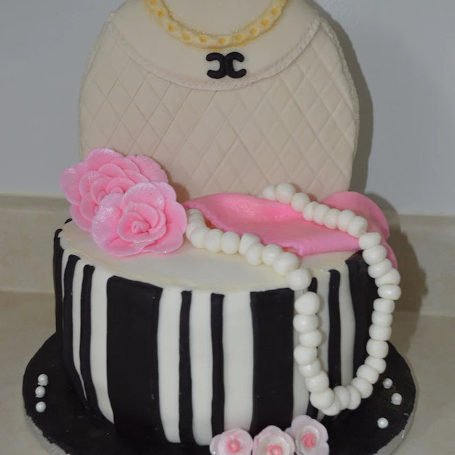 Cake topped with purse and pearls.